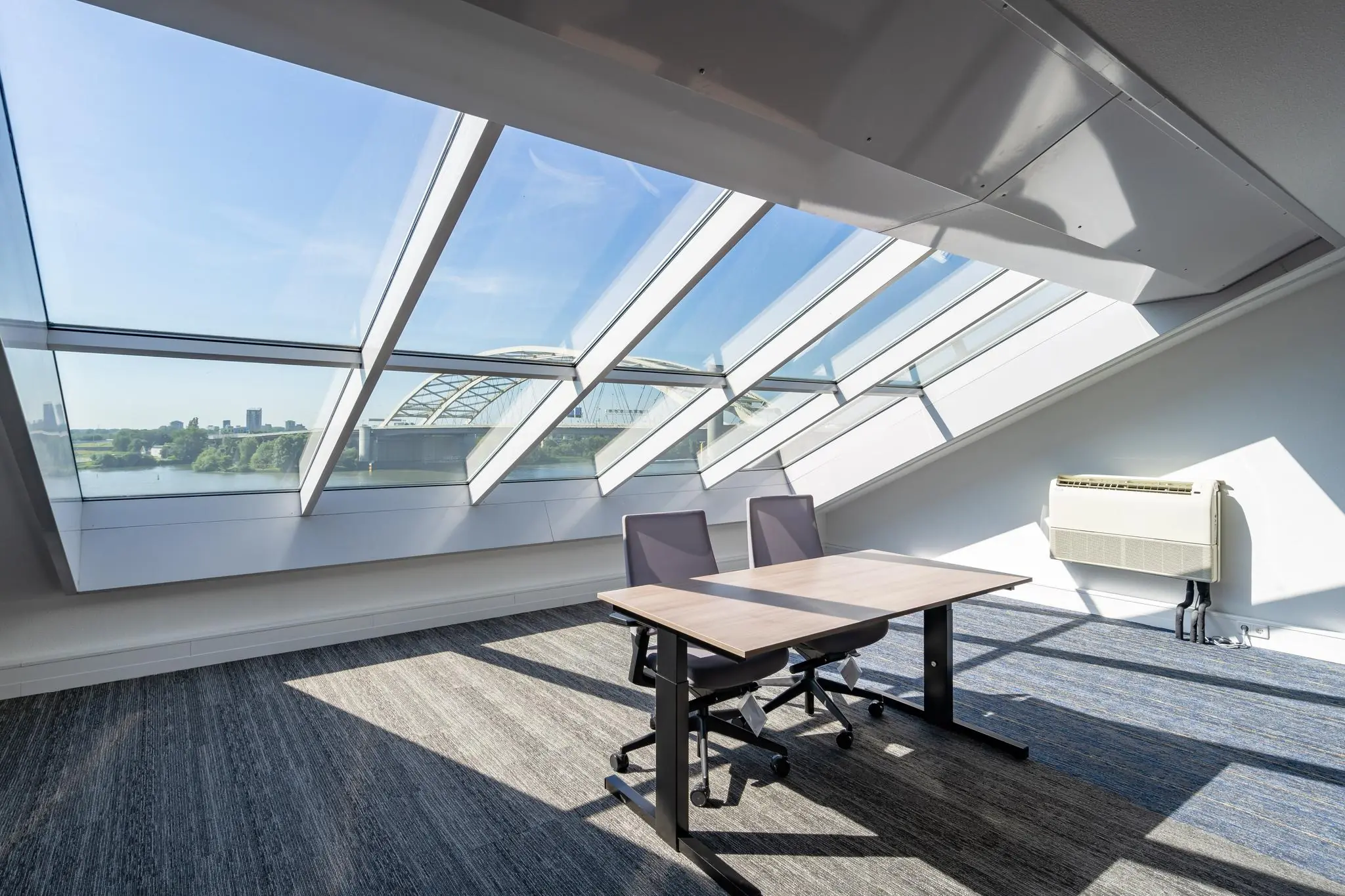 Licht kantoor met schuine ramen en uitzicht op de Rivium Promenade en een brug over het water.